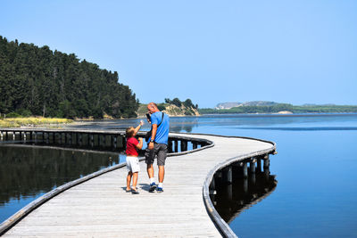 Father and son walking on footbridge over sea