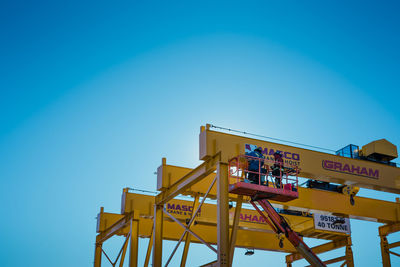Low angle view of information sign against clear blue sky
