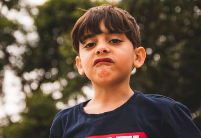 Portrait of boy making a face against trees