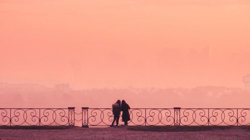 Silhouette woman standing by sea against sky during sunset