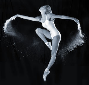 Full length of woman dancing against black background