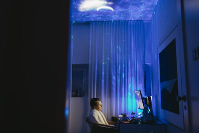 Boy at desk using computer at night