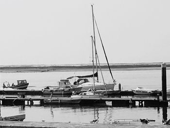 Sailboats moored at harbor against clear sky