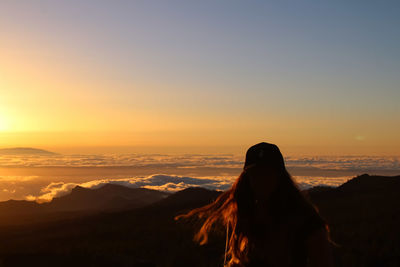 Silhouette woman standing on mountain against sky during sunset