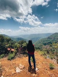 Rear view of woman standing on mountain against sky