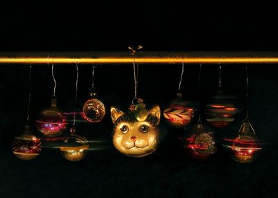 Close-up of illuminated lanterns hanging against black background