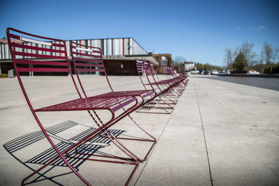 Empty chairs by railing against clear blue sky