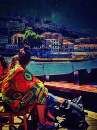 People sitting on illuminated city street at night