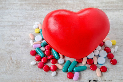 High angle view of heart shape and multi colored medicines on table