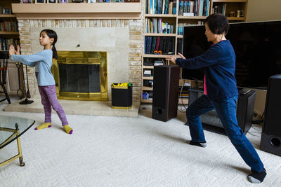 Asian grandmother teaching granddaughter tai-chi at home