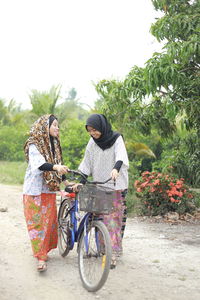 Sisters with bicycle on dirt road