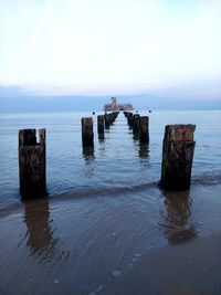 Wooden posts on sea against sky