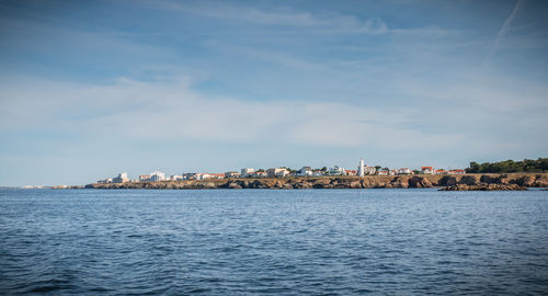 Sea by buildings against sky