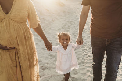 Young family of three walking and playing at beach