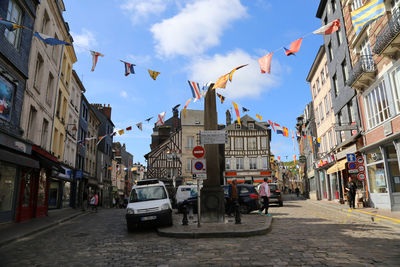 Cars on street amidst buildings in city against sky