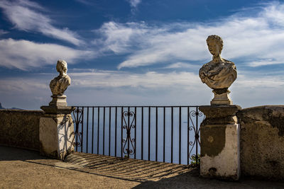 Statue by railing against sky