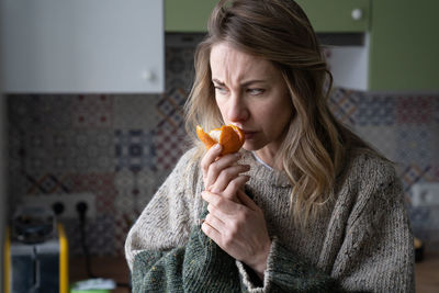 Woman smelling orange at home