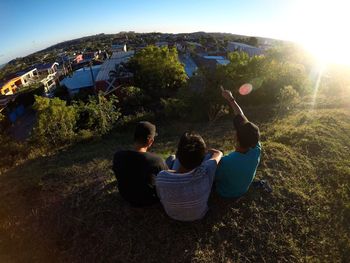 People sitting on rock against sky