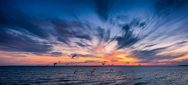 Scenic view of sea against dramatic sky during sunset