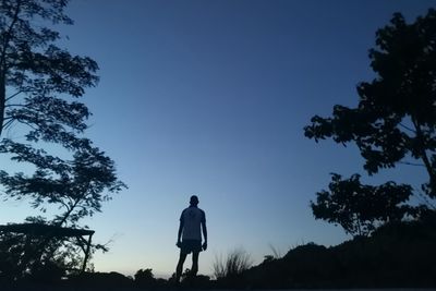 Rear view of silhouette man standing on field against sky