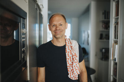 Portrait of smiling mature man doing housework in kitchen