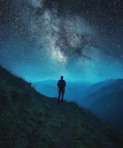 Silhouette man standing on mountain against star field at night