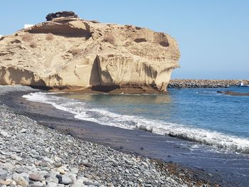 Rock formation on beach against clear sky