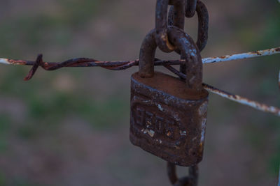 Close-up of rusty chain hanging on metal fence