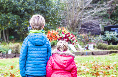 Siblings standing against flowers in graveyard