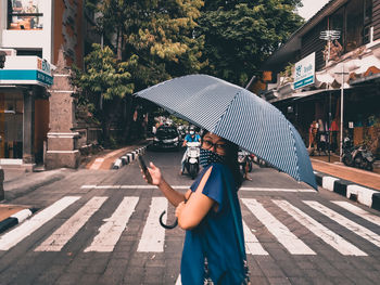 Man holding umbrella on wet street in rainy season