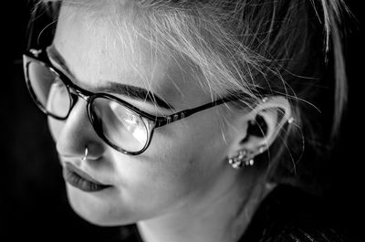 Close-up of young woman wearing eyeglasses in darkroom