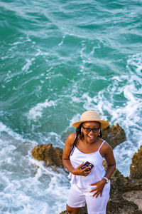 High angle view of a young woman listening to music at the beach whole holding her phone