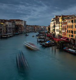 Canal amidst buildings in city against sky