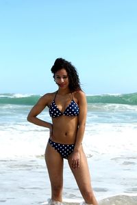 Young woman standing at beach against sky