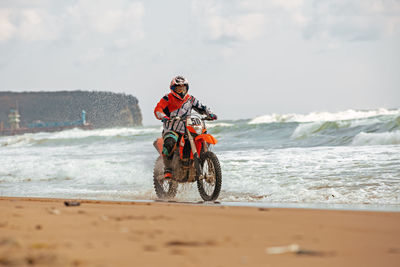 Horse riding motorcycle on beach against sky