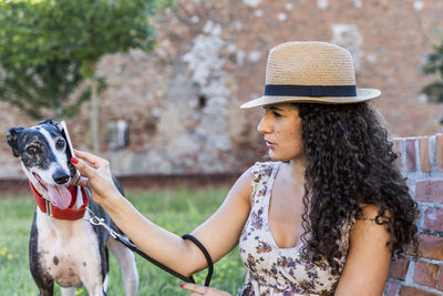 Woman holding smart phone on dog eat while sitting outdoors