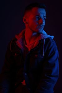 Portrait of young man looking away over black background