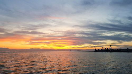 Scenic view of sea against dramatic sky during sunset