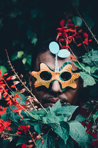 Portrait of man wearing mask while hiding by plants