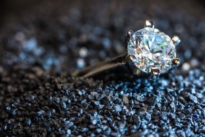 A ring with a cut gem lies on black sand