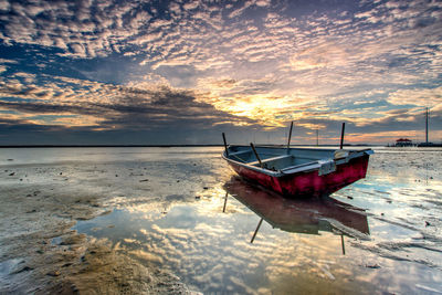 Boat on beach against sky during sunset
