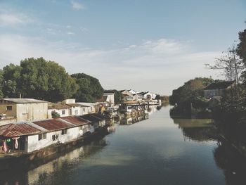 River amidst houses in town against sky