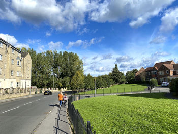 Man riding bicycle by road against sky in city