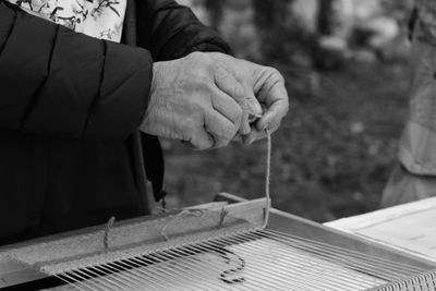 Midsection of man working with string