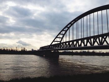 Bridge over river against cloudy sky