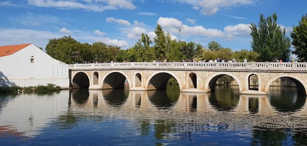 Arch bridge over river against sky