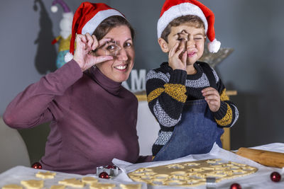 Portrait of smiling mother and son holding cookie cutters against eyes
