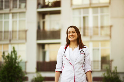 Young woman standing against building