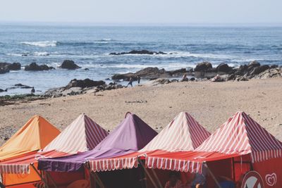 Deck chairs on beach against sky