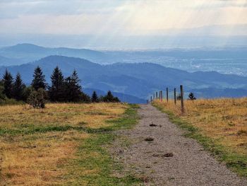 Scenic view of wandering path on top hill against moutain range